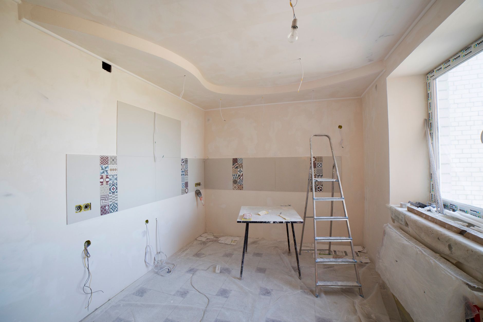 A kitchen under renovation with a ladder and tools