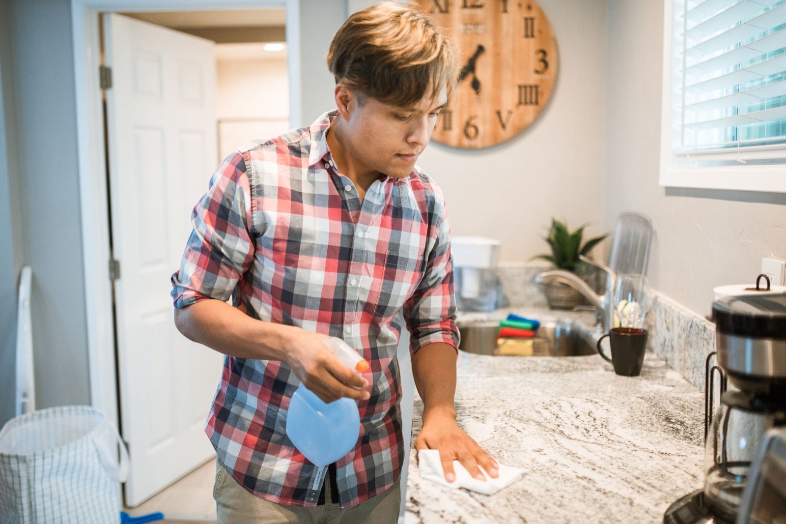 A house cleaner wiping down a kitchen counter with a spray bottle and cloth