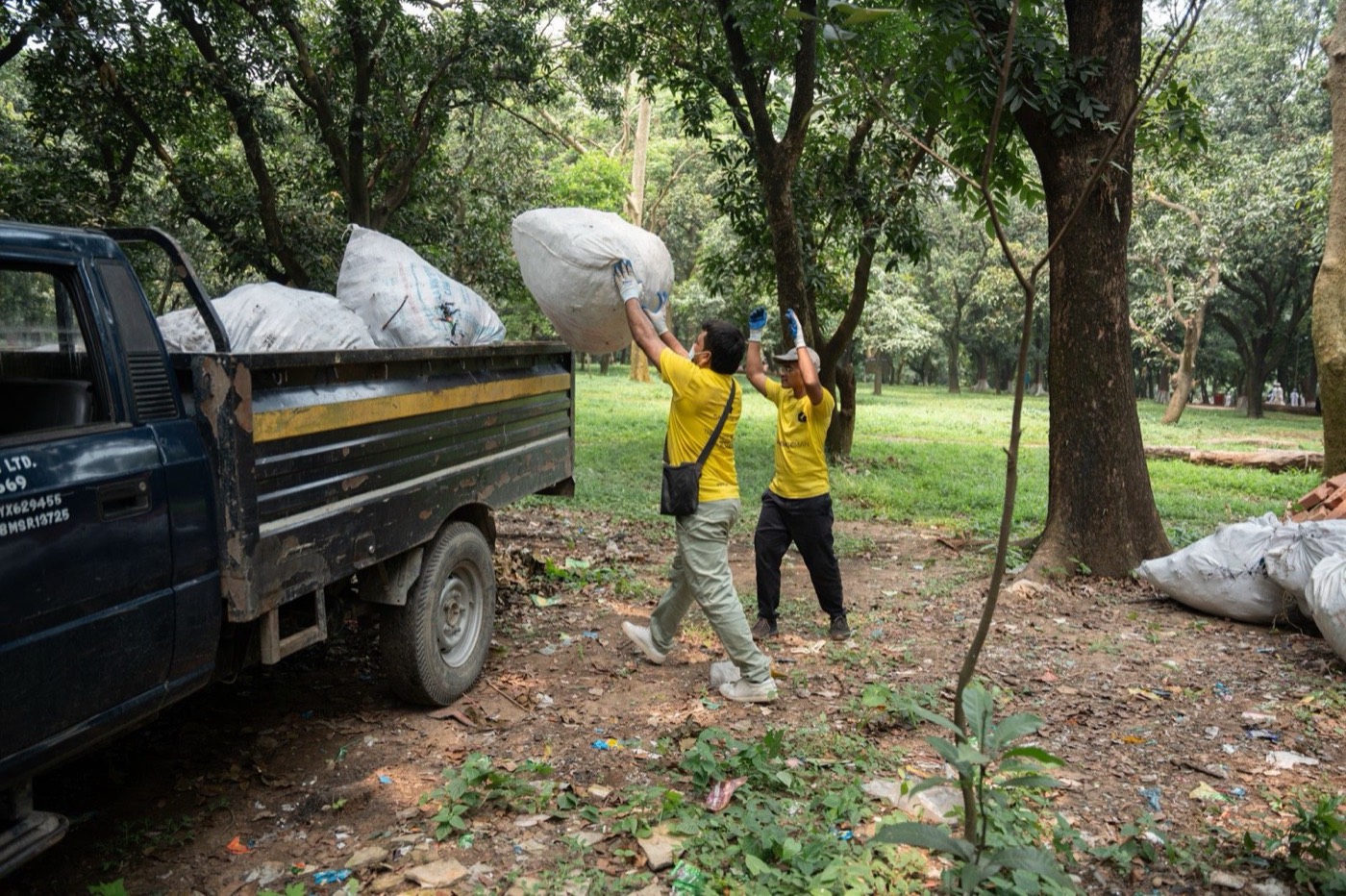 Two workers loading bags of debris into the back of a truck