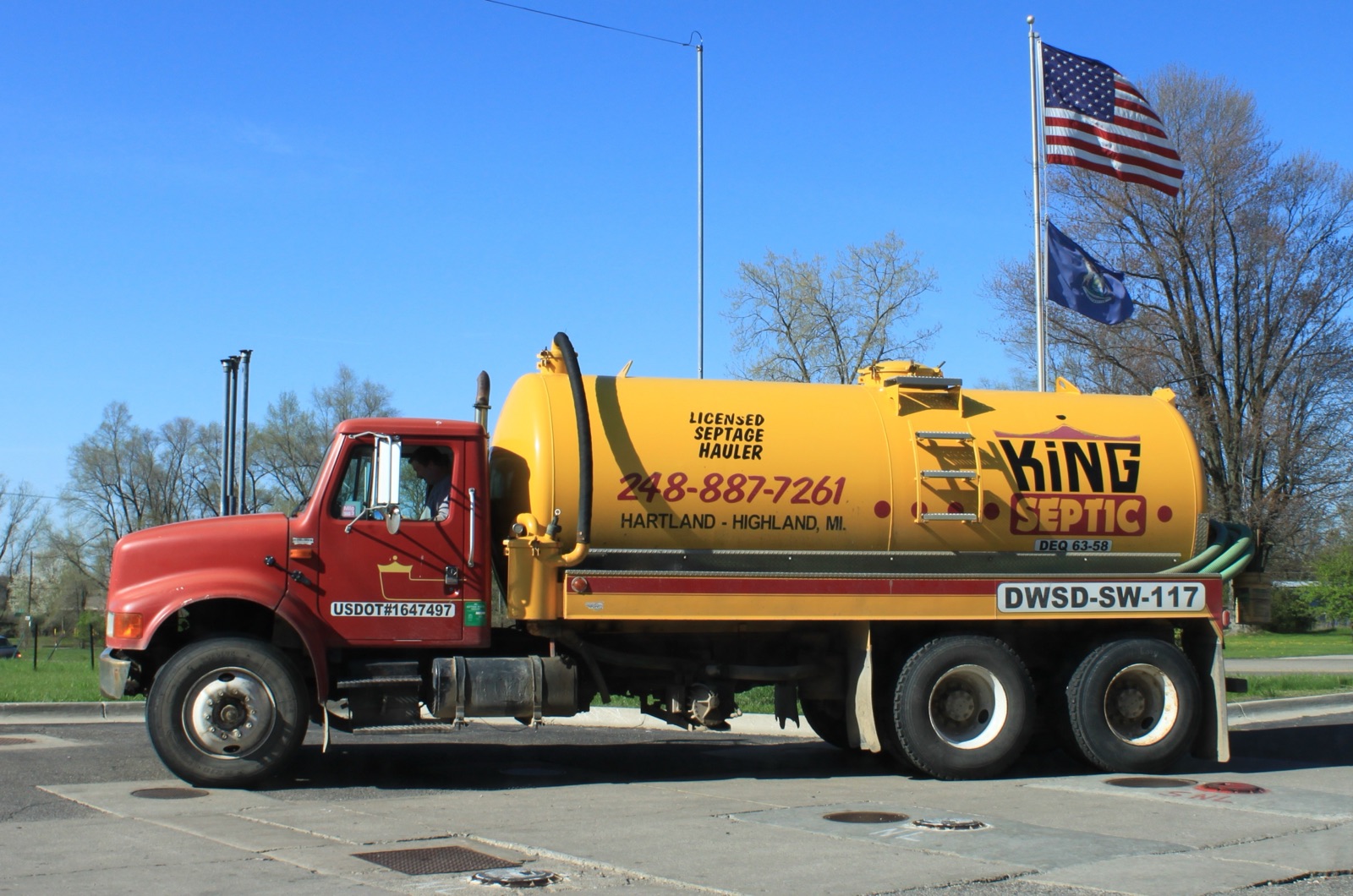 A red septic pumping truck parked outside a home