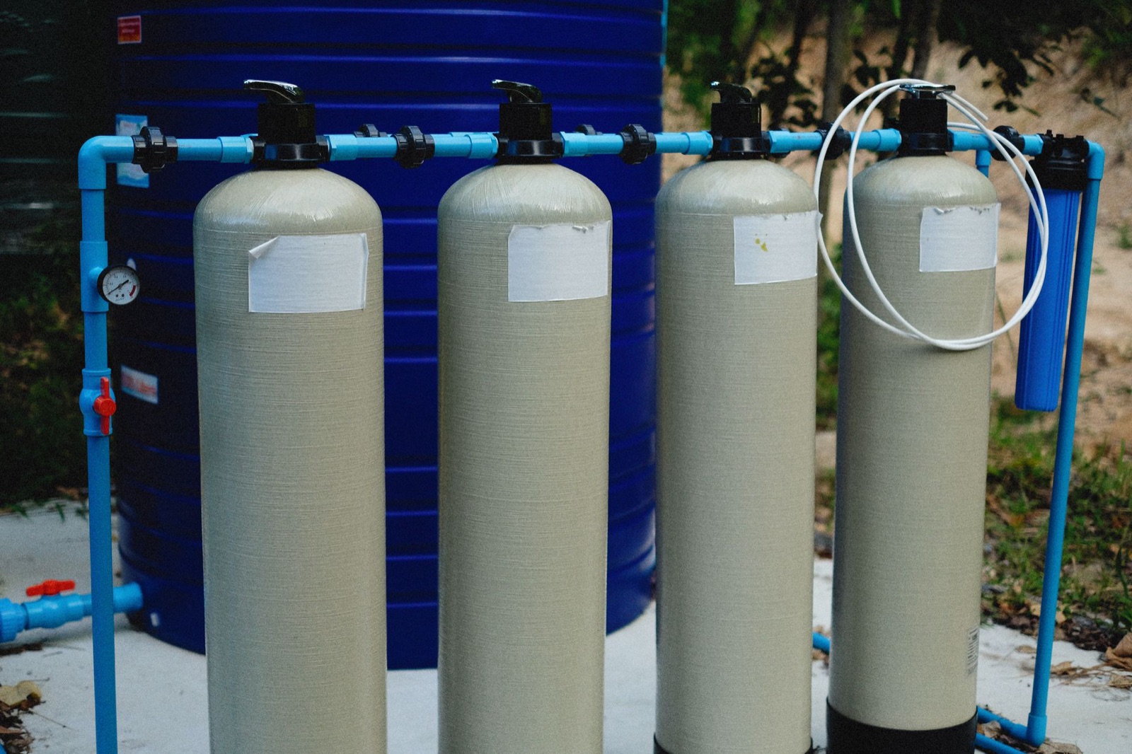 A row of tan water softener and filtration tanks plumbed together